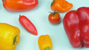 Mavi arka planda küçük ve büyük tatlı biber ve kiraz domatesleri karışımı.