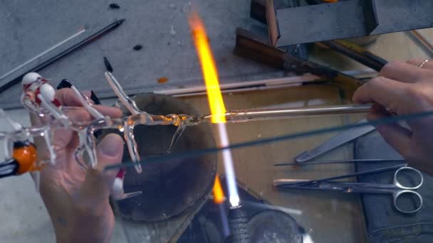 Крупный план мужских рук. делать стеклянные изделия, расплавляя стекло на горелке — стоковое видео