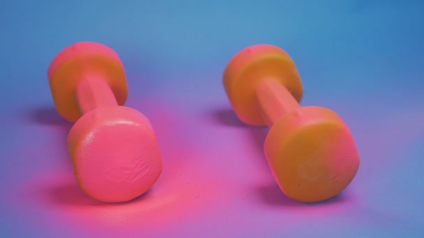 El proceso de colorear pesas de color naranja con pintura en aerosol rosa. fondo azul — Vídeo de stock