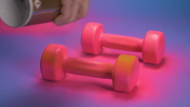 El proceso de colorear pesas de color naranja con pintura en aerosol rosa. fondo azul — Vídeo de stock