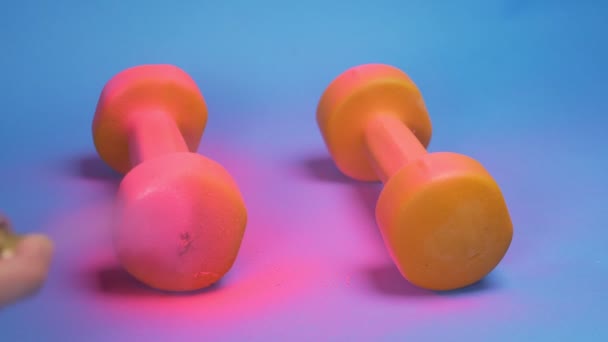 El proceso de colorear pesas de color naranja con pintura en aerosol rosa. fondo azul — Vídeos de Stock