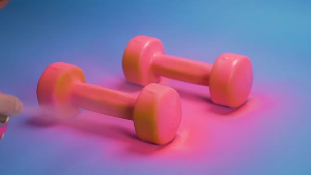 The process of coloring orange dumbbells with pink spray paint.  blue background — Stock Video