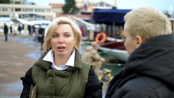 Twee mooie stijlvolle blonde vrouwen praten op een marine pier — Stockvideo