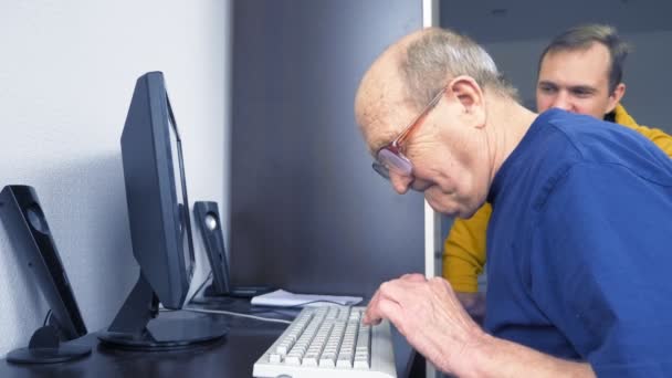 Joven y setenta viejo hombre uso de la computadora juntos — Vídeos de Stock