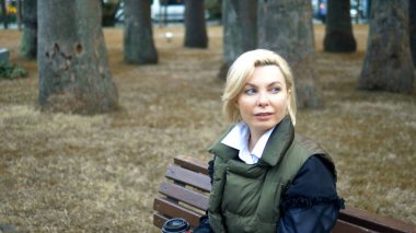 Güz Parkı 'nda bankta oturan şık sarışın kadın.