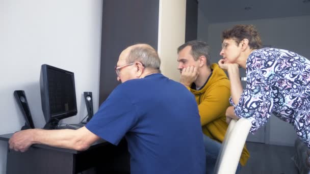 un jeune homme explique aux personnes âgées comment utiliser un ordinateur 