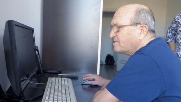 70-летний мужчина в очках, работающий за компьютером . — стоковое видео