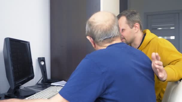 年轻人和七十岁老人一起使用计算机 — 图库视频影像