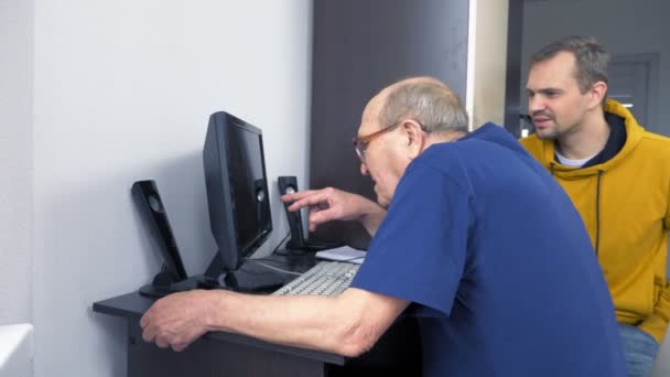 Молодой человек объясняет пожилым людям, как пользоваться компьютером — стоковое видео