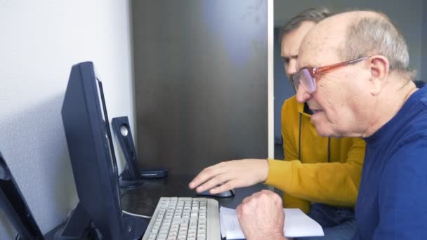 Joven y setenta viejo hombre uso de la computadora juntos — Vídeo de stock