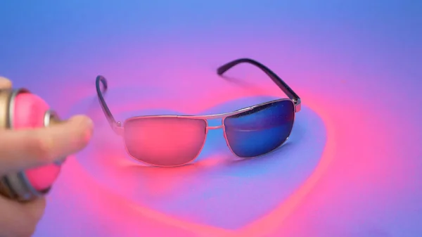 Les lunettes de soleil sont peintes en rose avec de la peinture en aérosol sur un fond bleu — Photo