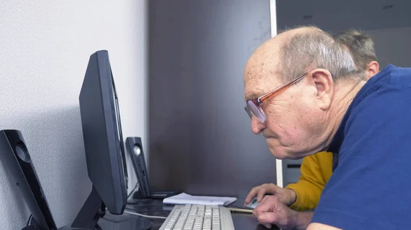 young man and seventy old man use computer together