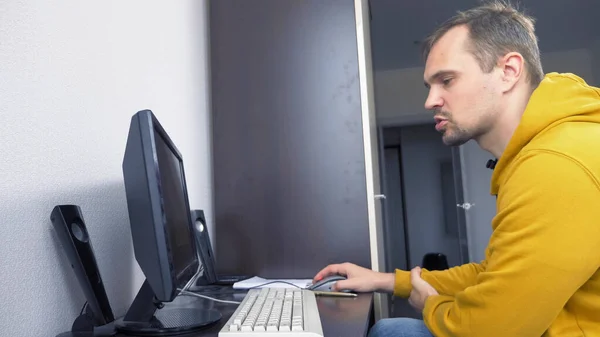 Разочарованный мужчина, сидящий дома за компьютерным столом — стоковое фото