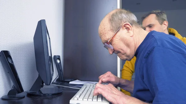 Joven y setenta viejo hombre uso de la computadora juntos —  Fotos de Stock