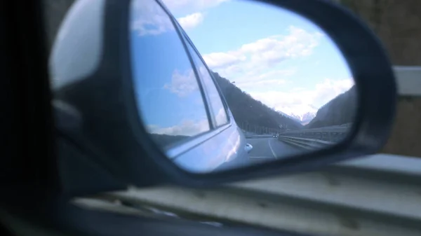 Montanhas nevadas refletidas no espelho retrovisor enquanto o veículo está em movimento — Fotografia de Stock