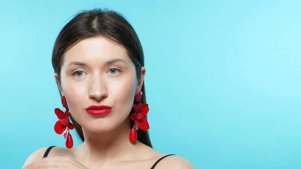 Young beautiful stylish girl wears earrings. blue background — Stock Photo, Image