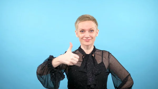 Elegant woman showing thumbs up. looking at the camera. blue background — 图库照片