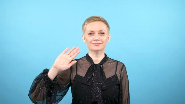 Stylish elegant woman is waving. blue background. gestures — Stok fotoğraf