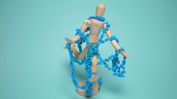 Turquoise jewelry hangs on a wooden human mannequin. blue background — Stok video