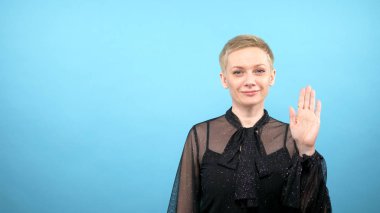 Stylish elegant woman is waving. blue background. gestures