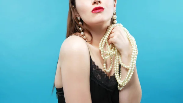 Young beautiful girl wears a necklace of white pearls. blue background — Stock Photo, Image