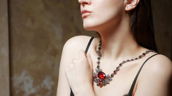 La chica se prueba un enorme collar hermoso con piedras rojas . — Foto de Stock