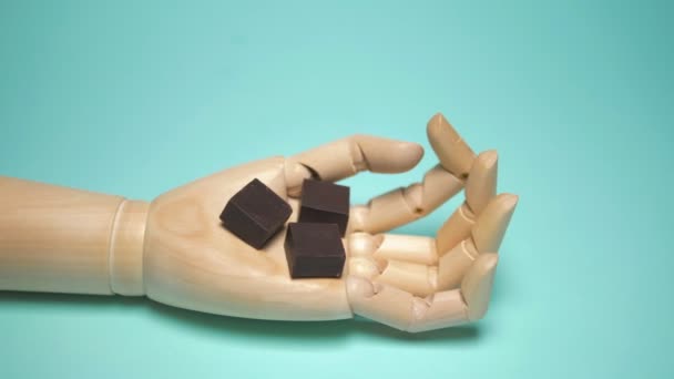 Wooden hand holds pieces of chocolate. trendy fashion design. blue background — Stok video