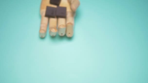 Die hölzerne Hand hält Schokoladenstücke. trendiges Modedesign. blauer Hintergrund — Stockvideo