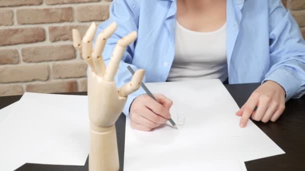 Beautiful girl, the artist makes a sketch of an artificial wooden hand. — Stok video