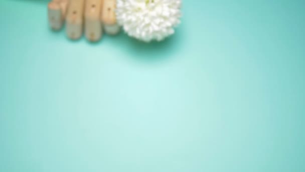 Houten hand met kunstmatige bloemen. blauwe achtergrond — Stockvideo