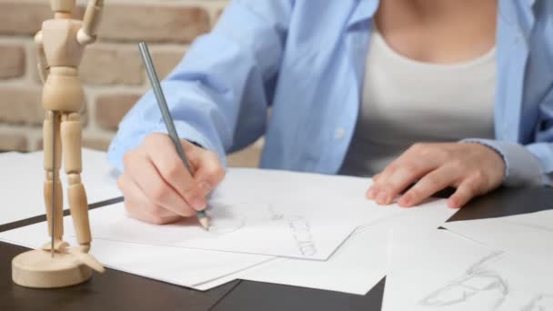 Artist girl draws a pencil sketch from a wooden figure of a man — 비디오