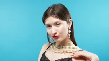 young beautiful girl wears a necklace of white pearls. blue background