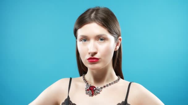 Девушка примеряет огромное красивое ожерелье с красными камнями. голубой фон — стоковое видео