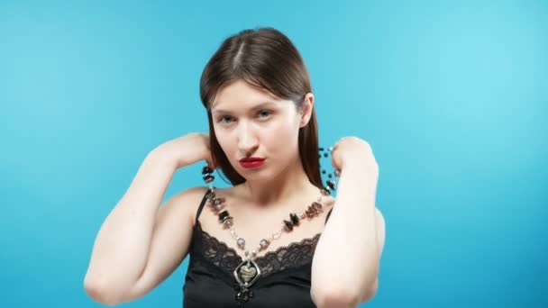 Young beautiful girl wears a black agate necklace. blue background — Stok video