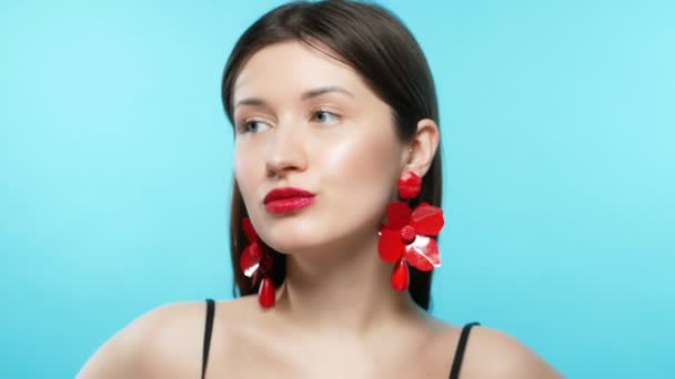 Jong mooi stijlvol meisje draagt oorbellen. blauwe achtergrond — Stockvideo