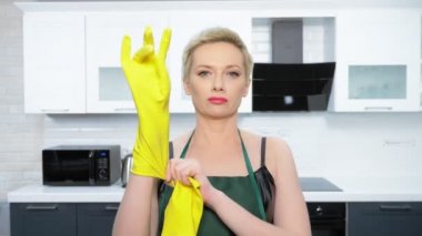  humor. woman in leather corset, puts on rubber gloves. cleaning