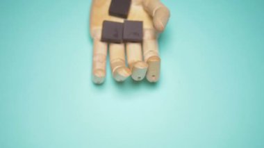 wooden hand holds pieces of chocolate. trendy fashion design. blue background