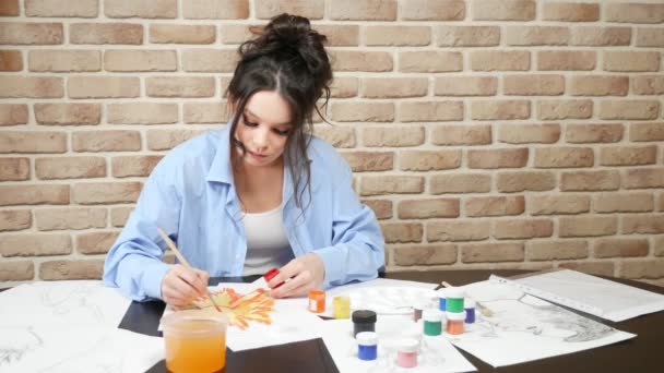 Beautiful young girl draws paints in the Studio . against a brick wall — 图库视频影像