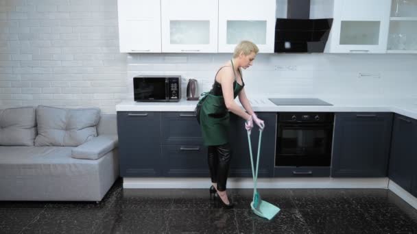 Χιούμορ. γυναίκα με δερμάτινο παντελόνι και ποδιά που σκουπίζει το πάτωμα — Αρχείο Βίντεο