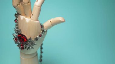 necklace with ruby hanging on a wooden mock hands. blue background