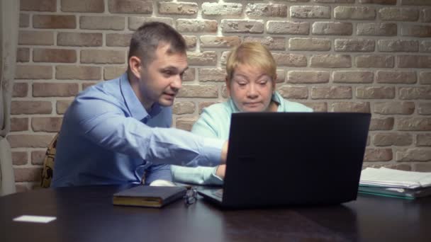 Starší žena a mladý muž pomocí notebooku společně proti cihlové zdi — Stock video