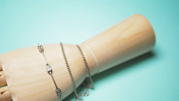 Silver jewelry hanging on wooden layout hands. stylish design. blue background. — Stock Video