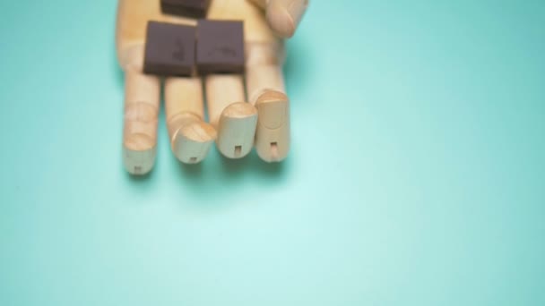 Wooden hand holds pieces of chocolate. trendy fashion design. blue background — Stock Video