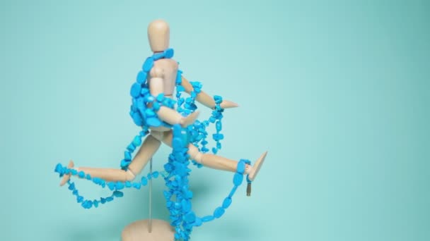 Turquoise jewelry hangs on a wooden human mannequin. blue background — Stock Video