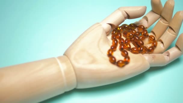 Beads of amber on a wooden arm. blue background. copy space — Stock Video