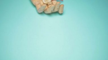 wooden hand holding artificial flowers. blue background