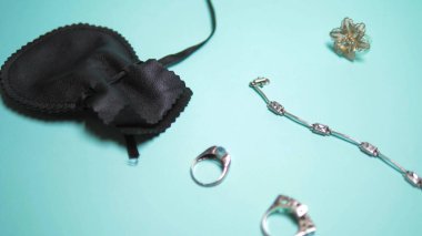 silver jewelry and black pouch on a blue background