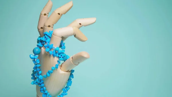 turquoise jewelry hanging on a wooden mock hands. blue background