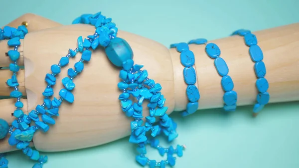 Bijoux turquoise accrochés sur une fausse main en bois. fond bleu — Photo