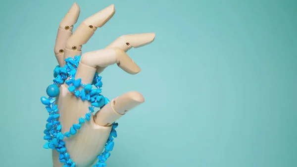 turquoise jewelry hanging on a wooden mock hands. blue background